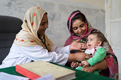 A doctor checks a baby held in her mother's arms in Northern Pakistan