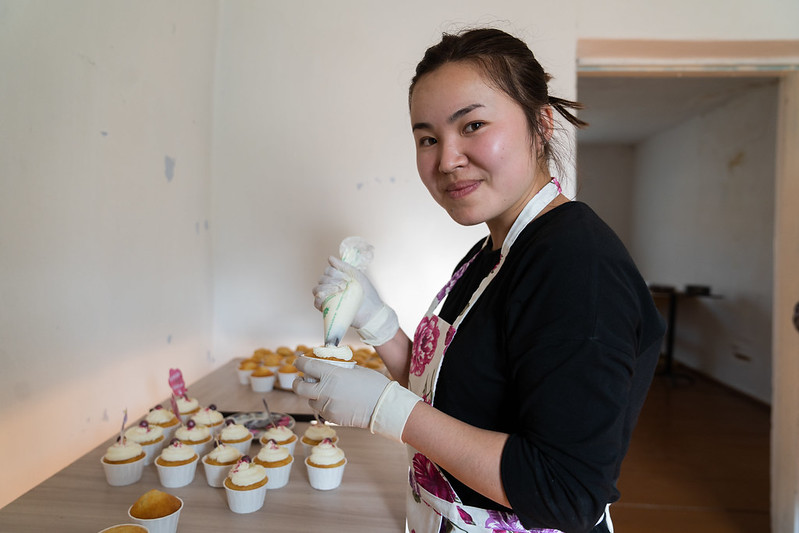 A woman smiles while frosting cupcakes in Kyrgyz Republic