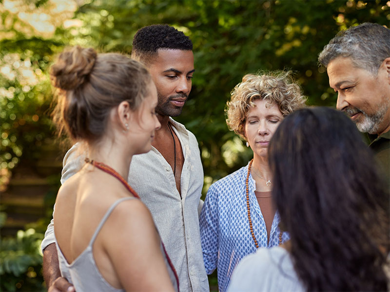 A group of diverse people stand in a circle with eyes closed A group of diverse people stand in a circle with eyes closed