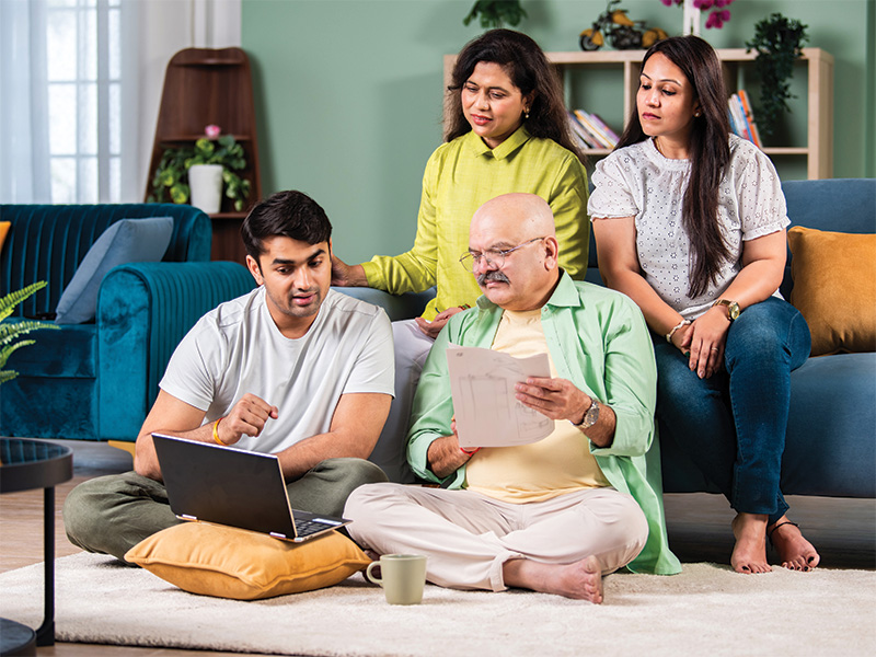 A Family sits together looking at a laptop and paperwork.