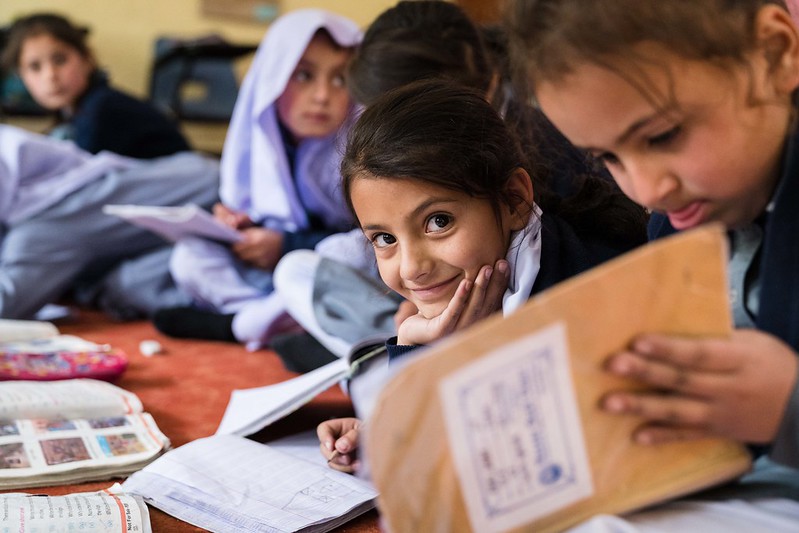 A young girl smiles while she does schoolwork in Pakistan