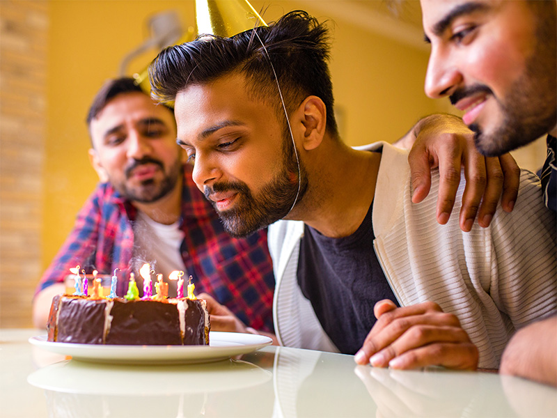 A young man blows out birthday candles with friends A young man blows out birthday candles with friends
